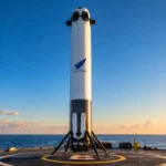 Booster de la fusée New Glenn de Blue Origin posé verticalement sur une plateforme en mer au coucher du soleil