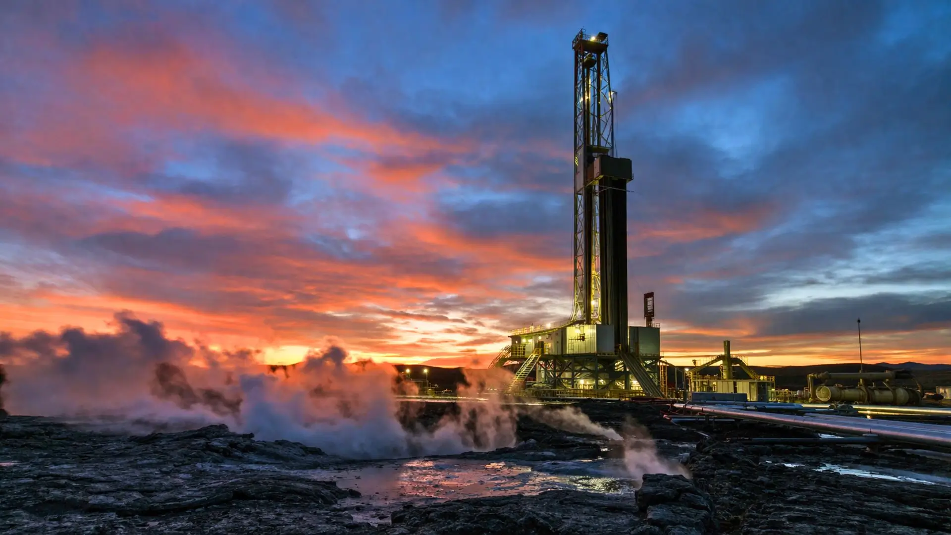 Un site de forage géothermique profond au crépuscule, avec une immense tour de forage, de la vapeur s’échappant du sol et des roches volcaniques sombres au premier plan.