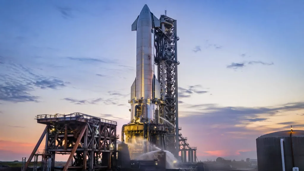 Une fusée Starship en acier inoxydable sur son pas de tir au Texas, au crépuscule, avec tour de lancement et infrastructures visibles.