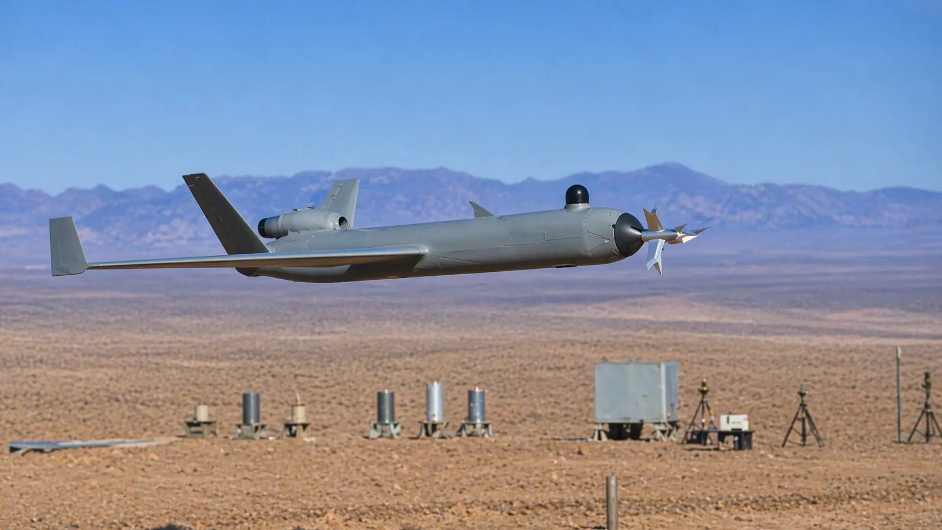 Drone militaire moderne avec lame frontale volant à basse altitude au-dessus d’un terrain d’entraînement désertique