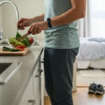 Homme préparant une salade de légumes frais dans une cuisine moderne pour une alimentation saine