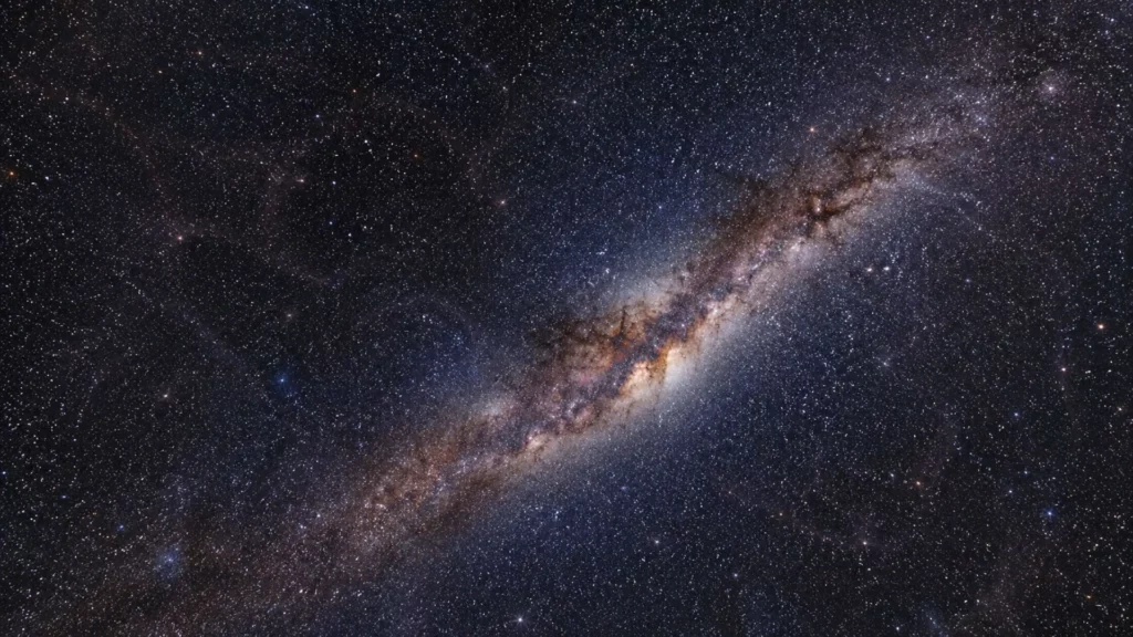 La Voie lactée traverse un ciel nocturne profond, avec une structure lumineuse très subtile évoquant un superamas de galaxies.