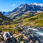 Vallée de montagne alpine avec rivière, roches et sommets enneigés, illustrant les zones géologiques propices à l’hydrogène naturel.