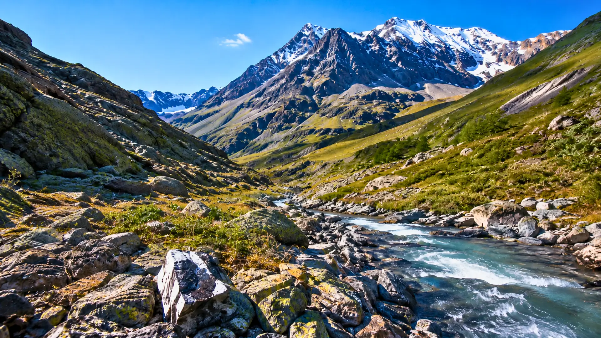 Vallée de montagne alpine avec rivière, roches et sommets enneigés, illustrant les zones géologiques propices à l’hydrogène naturel.