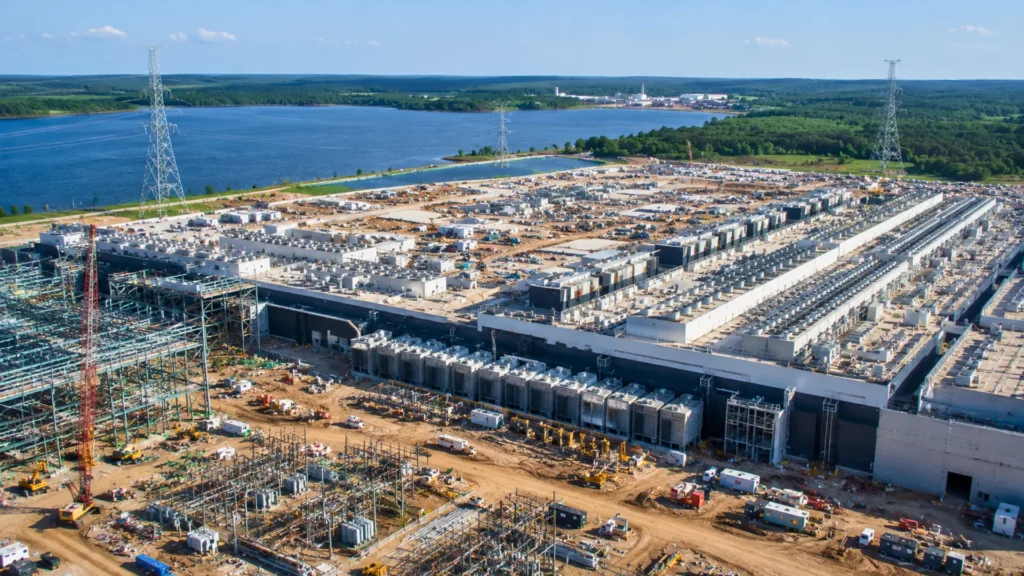 Vue aérienne d’un immense complexe industriel au Texas destiné à l’intelligence artificielle et aux infrastructures énergétiques près d’un lac artificiel.