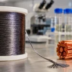 Bobine noire de fibre nanotube et faisceau de cuivre sur établi industriel.