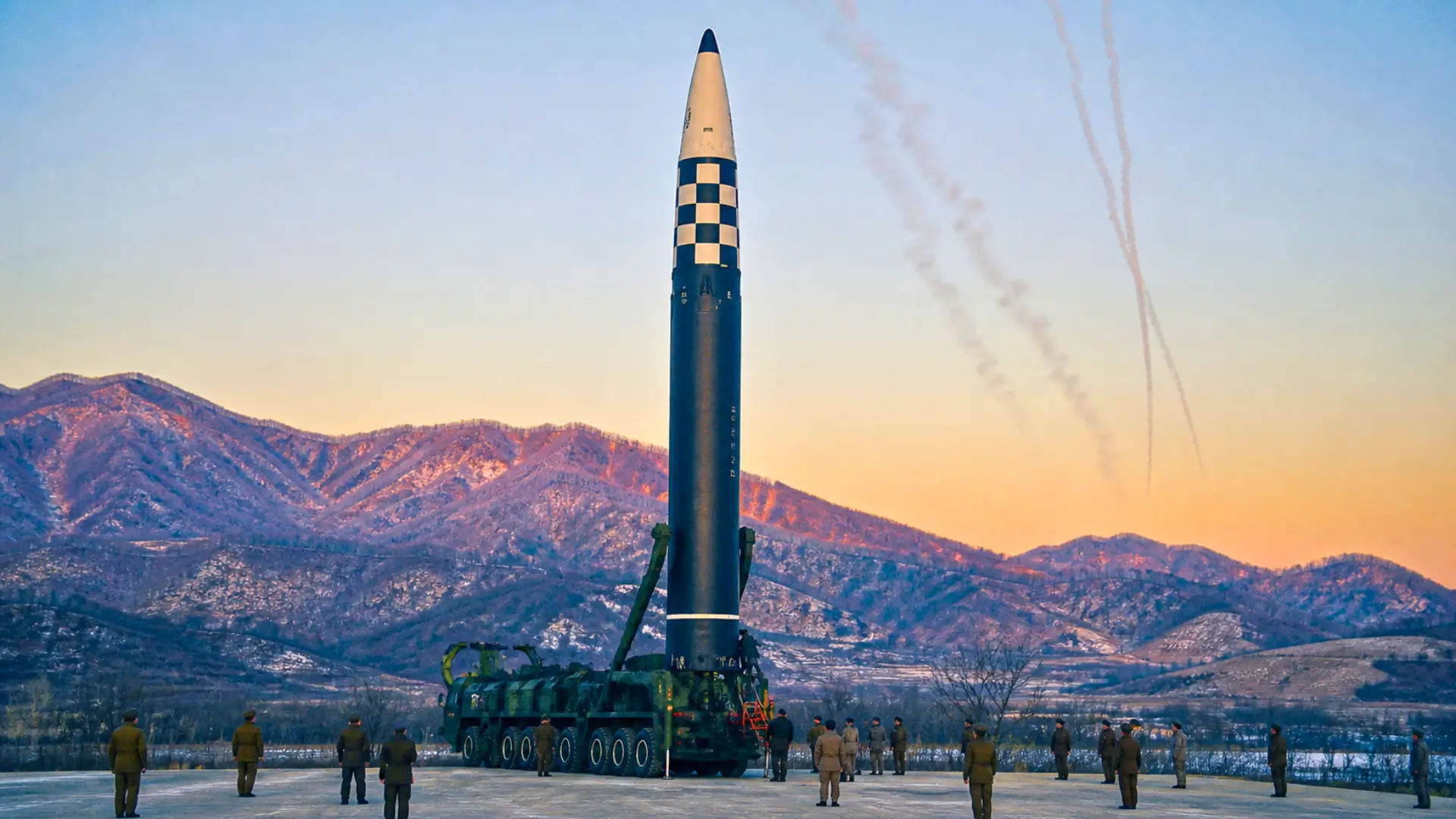 Missile balistique intercontinental nord-coréen sur une base militaire entouré de soldats dans un paysage montagneux