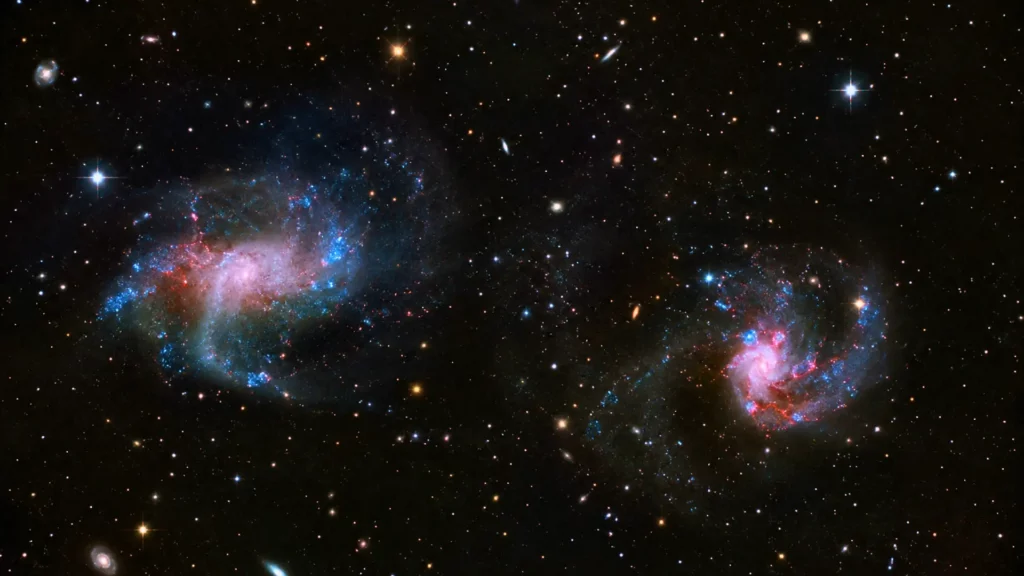 Deux galaxies lointaines brillent dans l’espace profond, entourées de gaz lumineux et d’étoiles, illustrant des trous noirs supermassifs observés par le télescope James Webb.