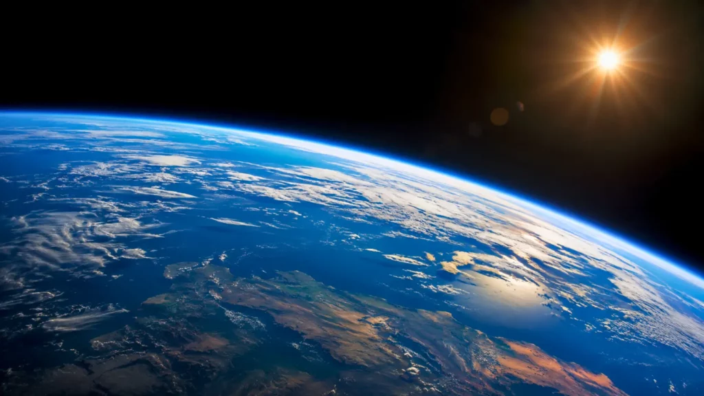 Vue réaliste de la Terre depuis l’espace, avec son atmosphère bleue éclairée par le Soleil.