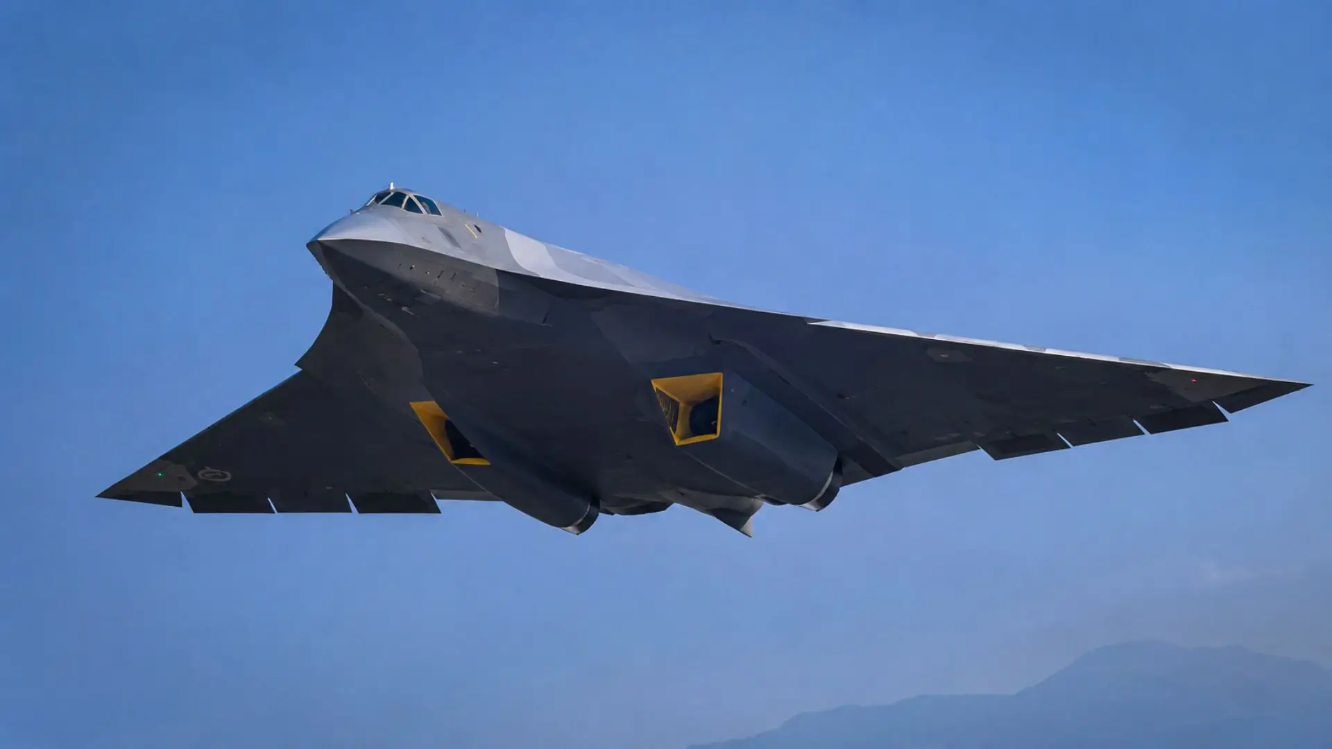 Un prototype de chasseur furtif chinois sans dérive verticale survole un ciel bleu, vu depuis le sol lors d’un vol d’essai.
