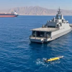 Navire militaire et drones maritimes sécurisant une voie de navigation stratégique.