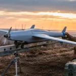 Drone à voilure fixe posé sur rail près d’une route logistique.