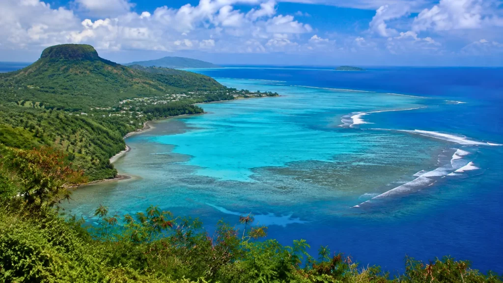 Vue panoramique du lagon turquoise de Mayotte, entouré de collines verdoyantes, de récifs coralliens et de l’océan Indien.
