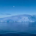 Immense paysage glacé de l’Antarctique au-dessus d’une mer calme, illustrant une formation géologique cachée sous la calotte polaire.