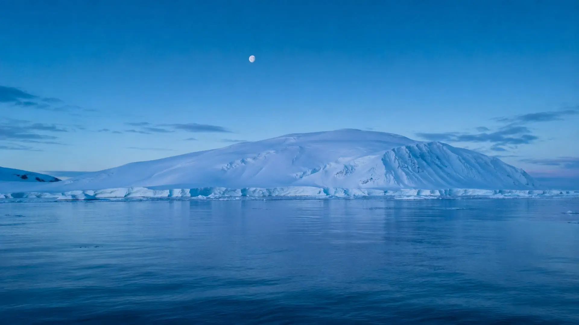 Immense paysage glacé de l’Antarctique au-dessus d’une mer calme, illustrant une formation géologique cachée sous la calotte polaire.