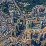 Vue aérienne d’une grande métropole dense, entre gratte-ciel, routes, quartiers résidentiels, chantiers et espaces verts.