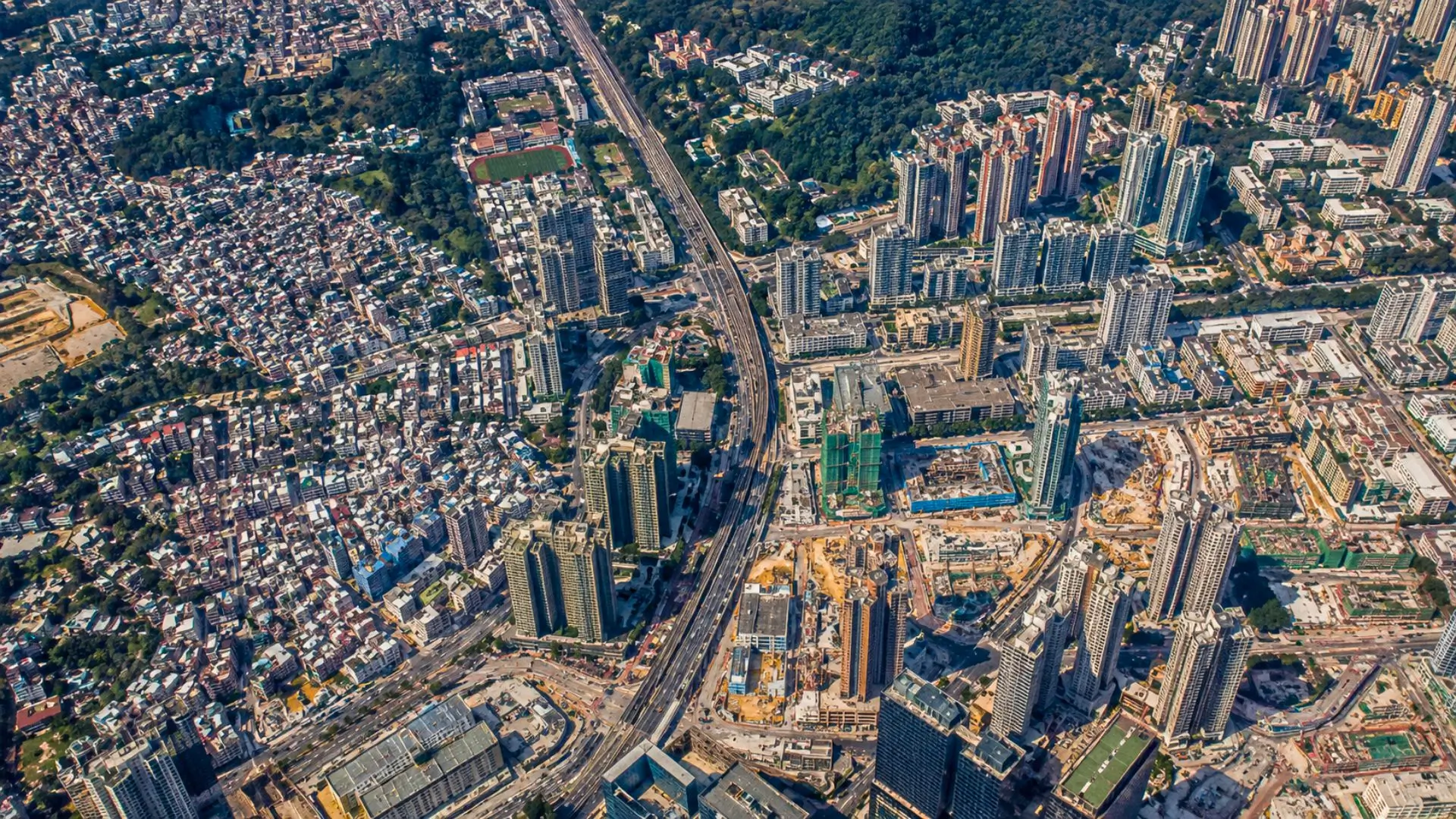 Vue aérienne d’une grande métropole dense, entre gratte-ciel, routes, quartiers résidentiels, chantiers et espaces verts.