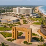 Complexe touristique côtier à Ouidah avec plage, amphithéâtre et navire historique.