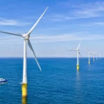 Parc éolien en mer avec turbines alignées au large d’une côte française.