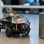 Un petit robot de laboratoire équipé d’un organoïde cérébral humain dans une boîte transparente s’approche d’un obstacle.