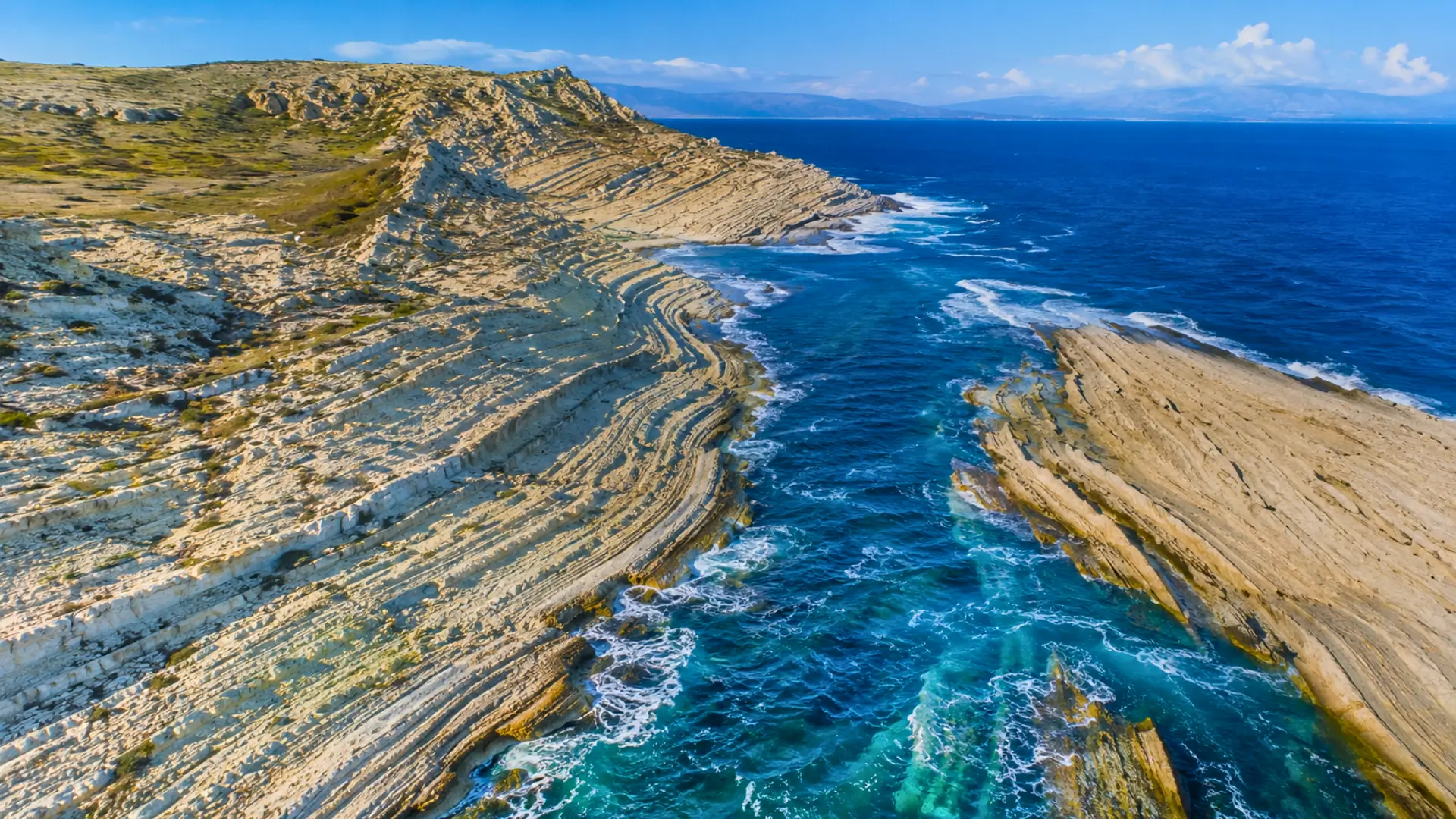 Vue aérienne réaliste de falaises calcaires striées en bord de Méditerranée, évoquant les traces géologiques d’un ancien mégaflot.