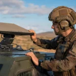 Un soldat français ajuste une antenne satellite intelligente installée sur un véhicule militaire en opération.