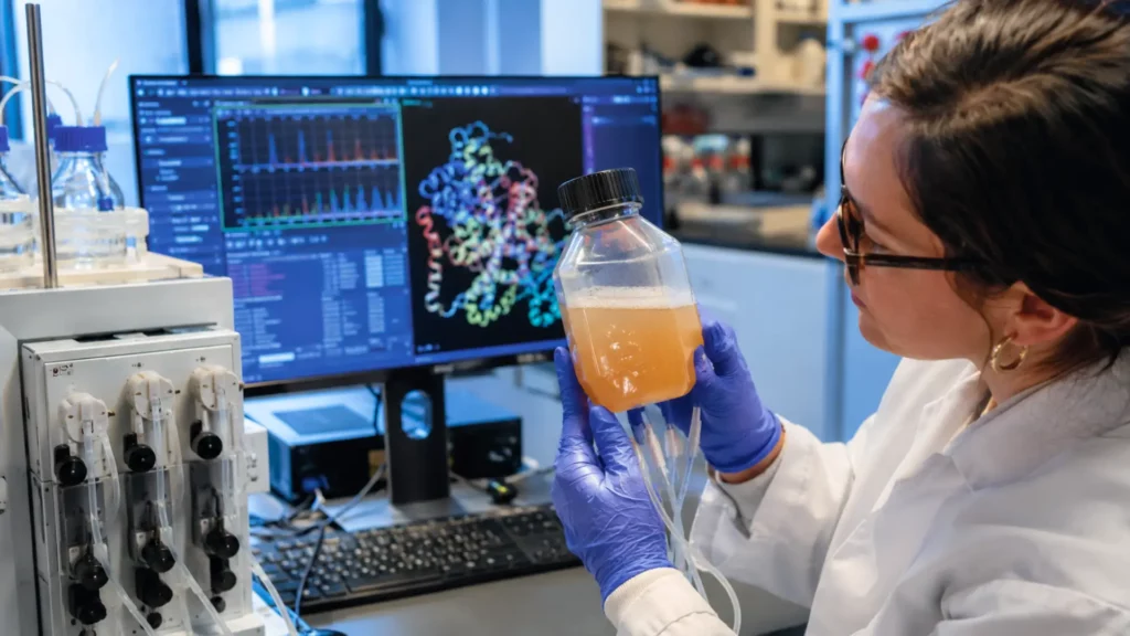 Chercheuse observant une culture bactérienne contenant une enzyme ancestrale recréée en laboratoire