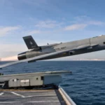 Un drone militaire autonome décolle depuis le pont d’un navire de la Royal Navy en pleine mer.