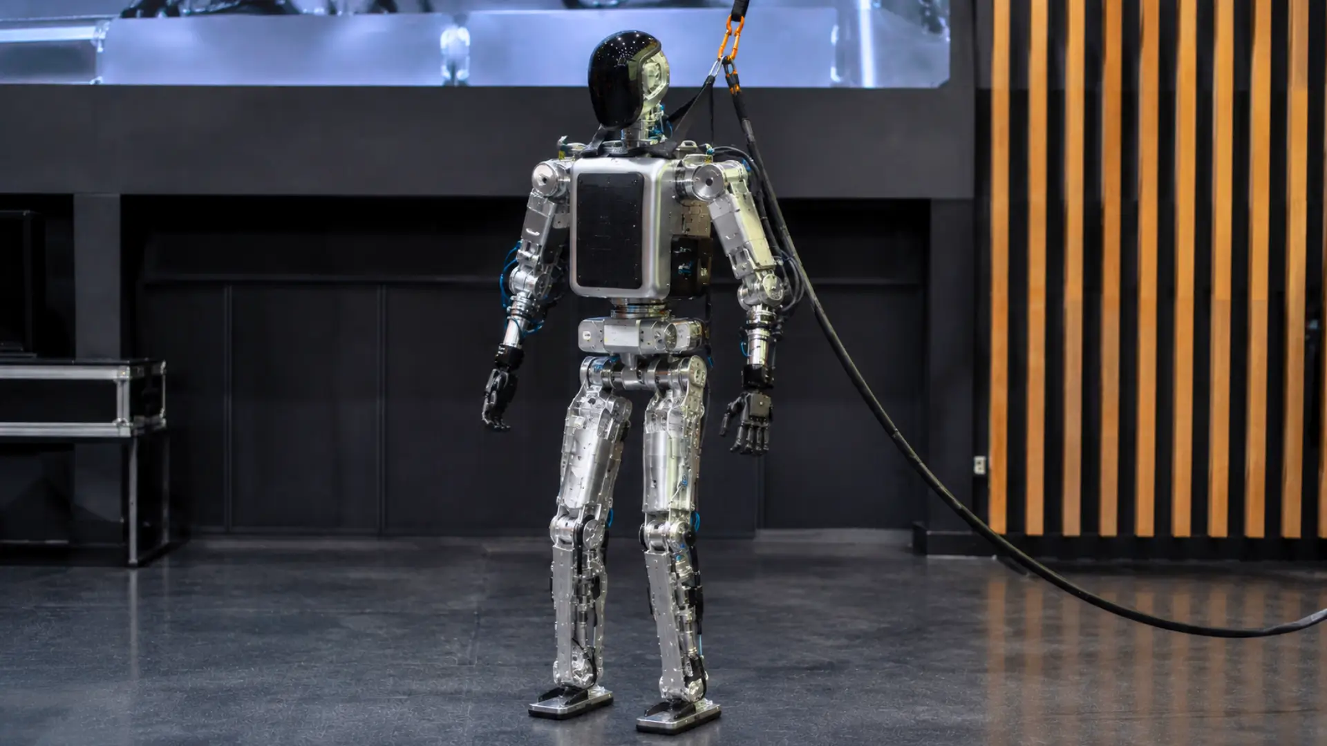 Robot humanoïde français Northstar debout dans un espace de démonstration, relié à un câble d’alimentation et à un harnais de sécurité.