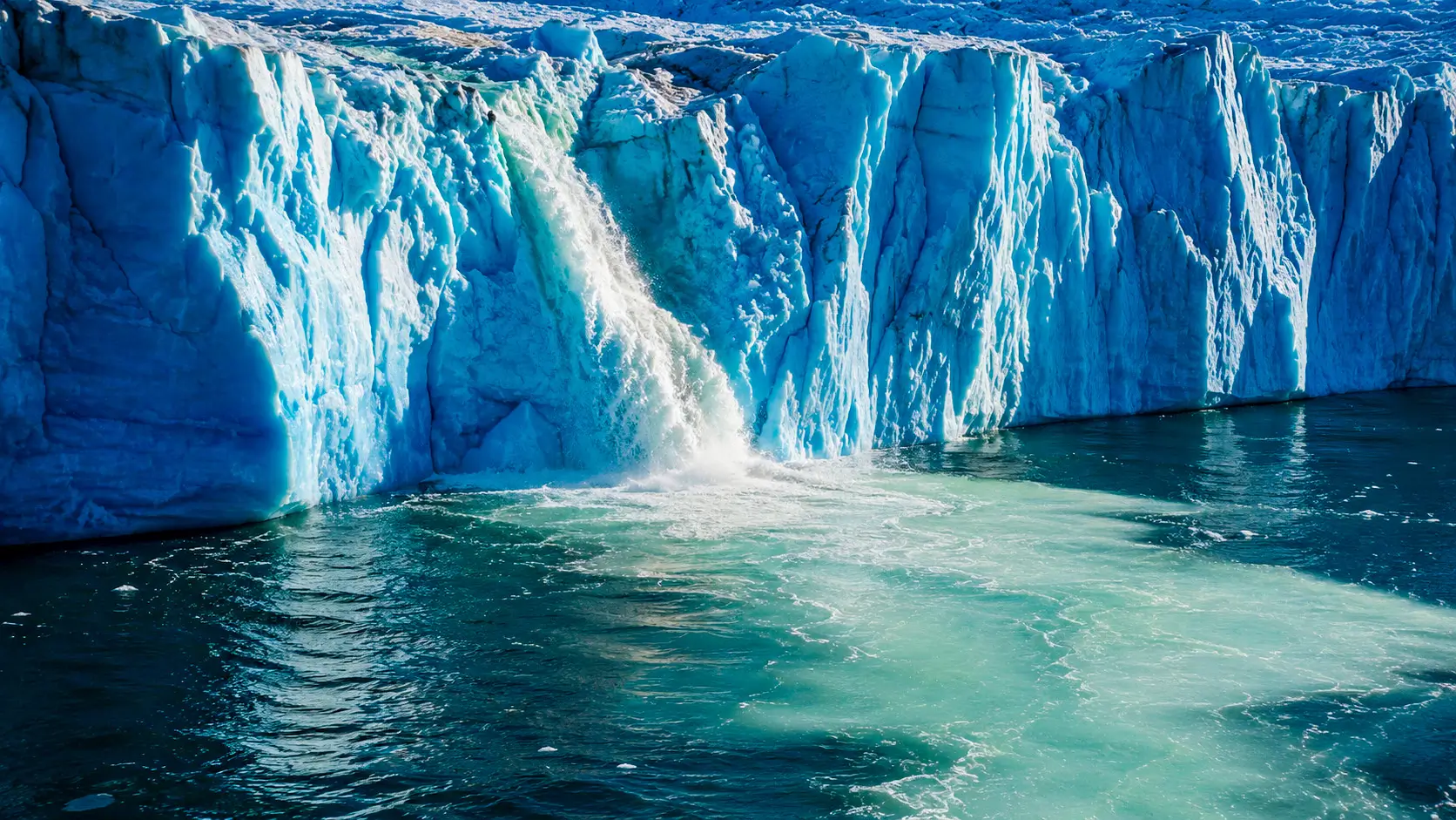 De l’eau de fonte s’écoule d’un glacier du Groenland et forme une vaste plume claire dans les eaux sombres de l’Atlantique Nord.