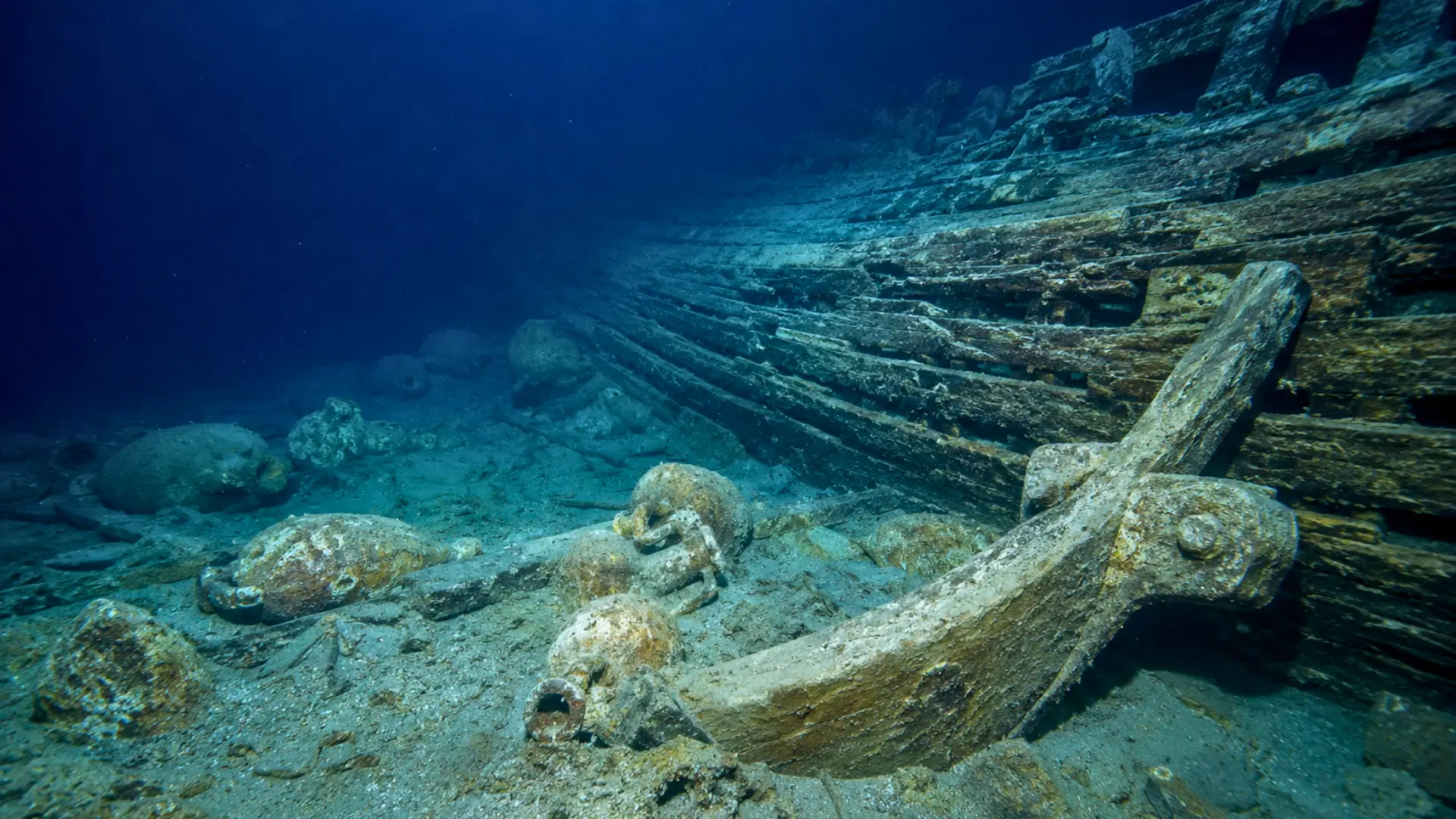 Épave grecque antique reposant sur le fond marin au large de Cannes, entourée d’amphores et de vestiges de coque en bois.