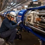 Une technicienne inspecte un aimant supraconducteur bleu dans le tunnel souterrain du Grand collisionneur de hadrons au Cern.