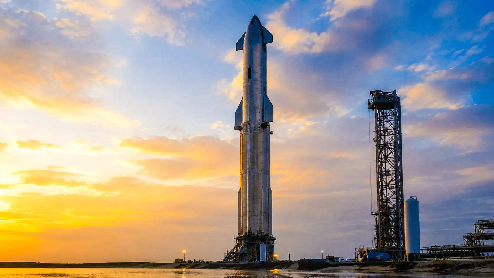 La fusée Starship dressée sur son pas de tir à Starbase, sous un ciel doré, avant une future mission vers Mars.