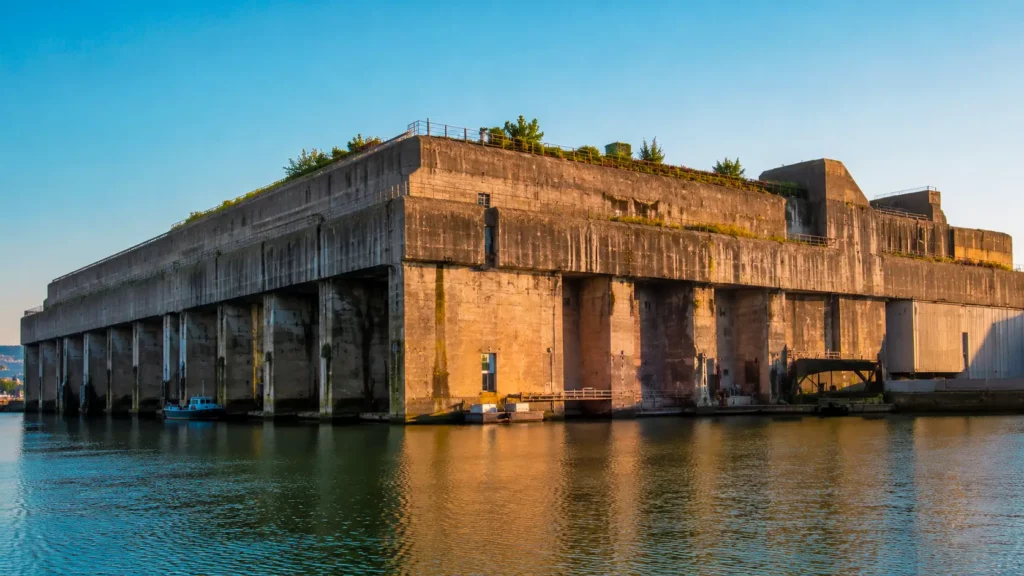 L’imposante base sous-marine en béton de Saint-Nazaire domine les eaux du port sous une lumière dorée.