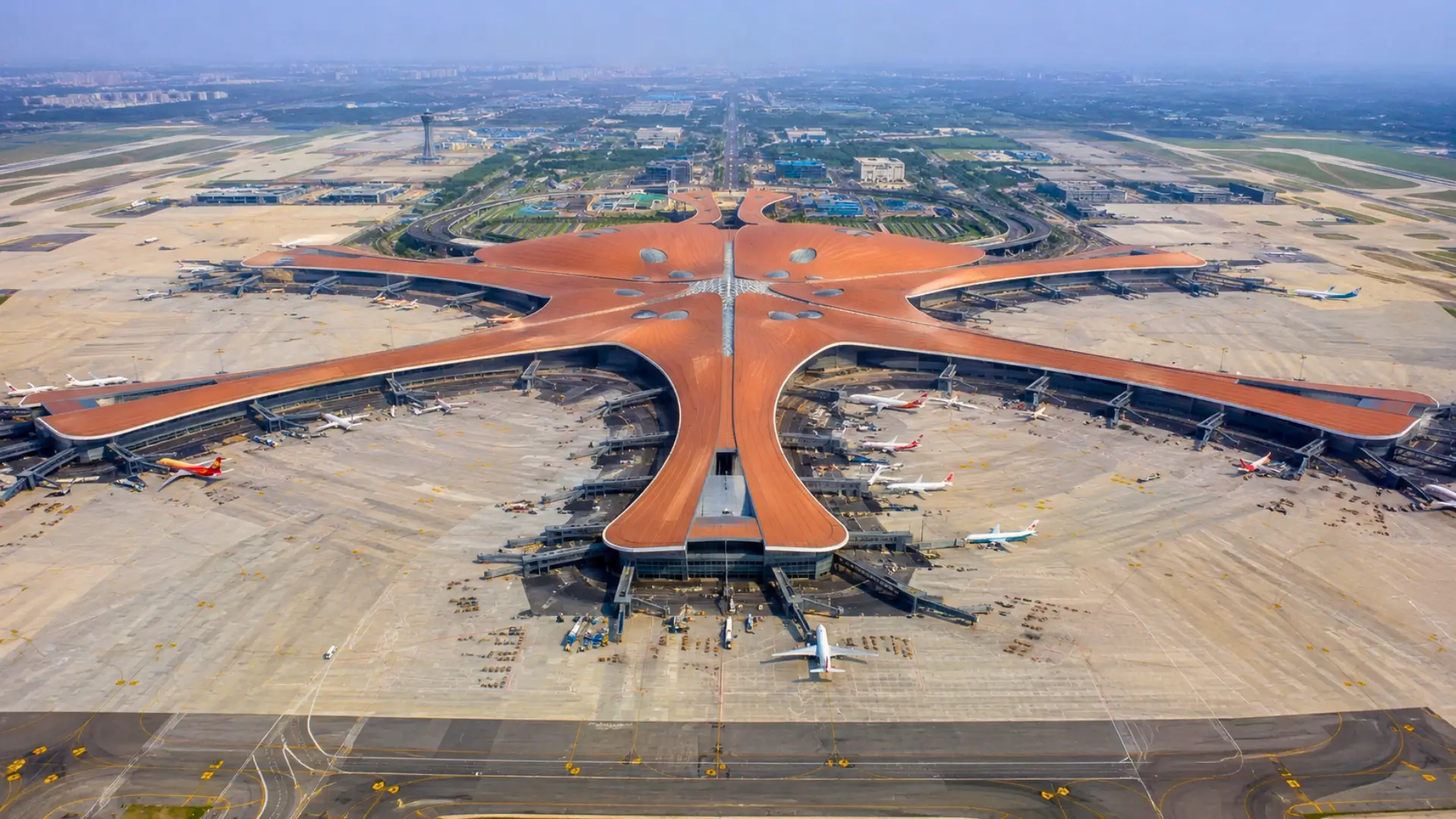 Vue aérienne de l’aéroport international Pékin-Daxing et de son immense terminal en forme d’étoile, entouré de pistes et d’avions.