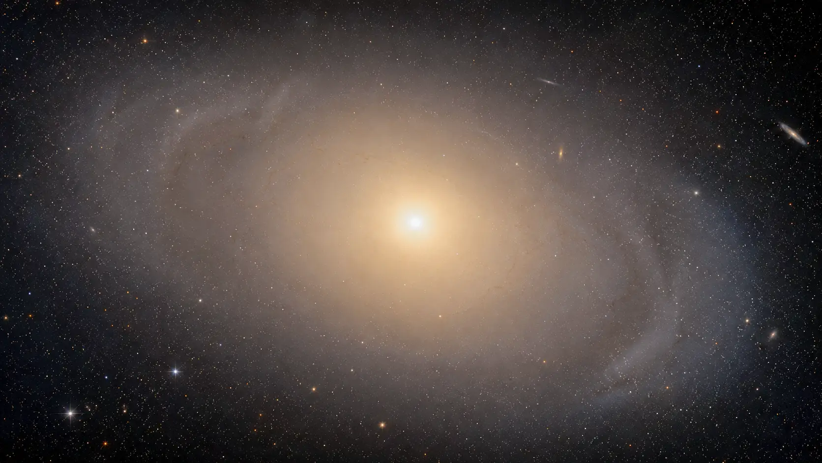La galaxie géante IC 1101 apparaît comme un immense halo lumineux doré entourant un noyau stellaire très brillant.