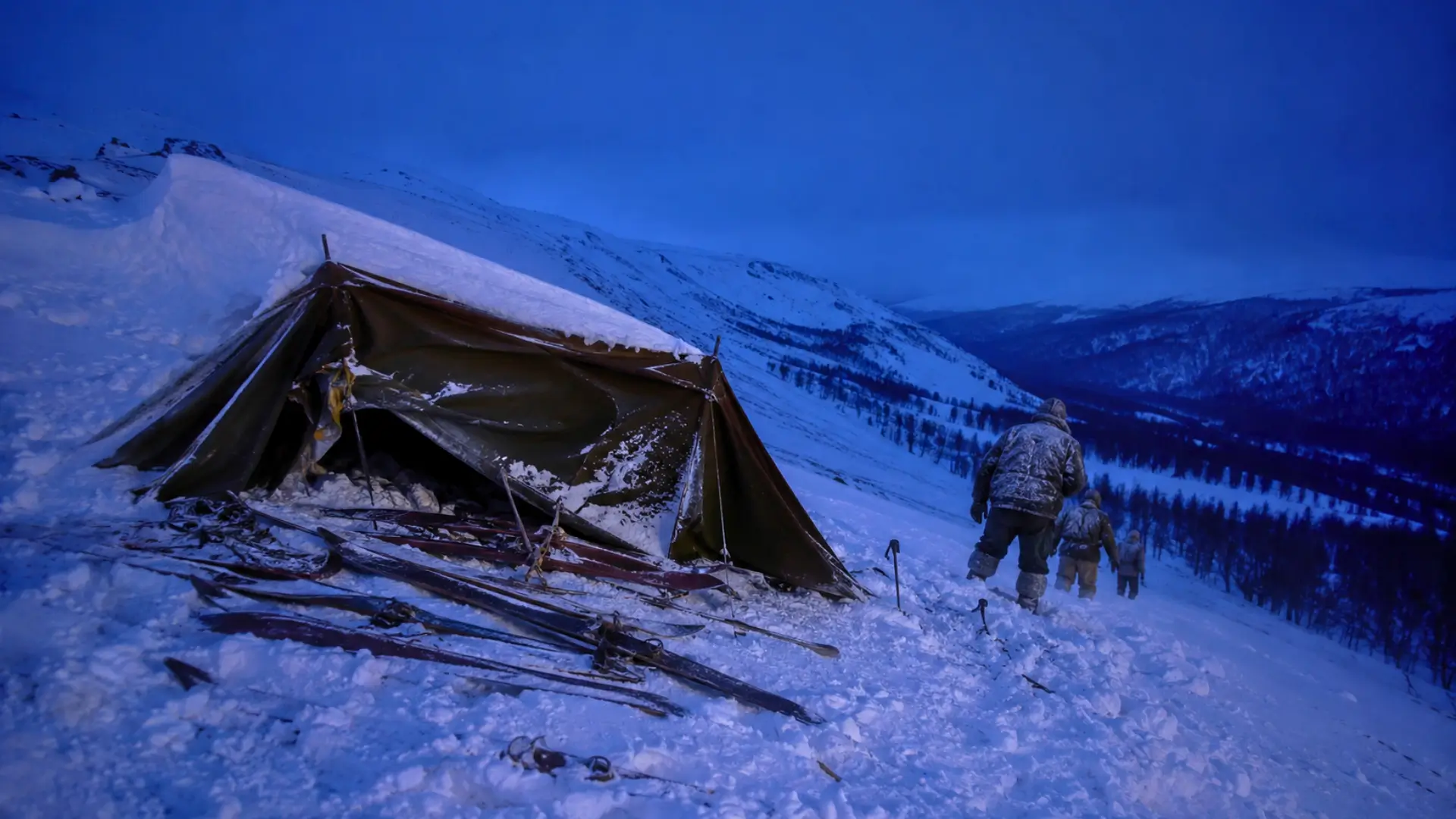 Tente endommagée dans la neige au col Dyatlov, avec des randonneurs descendant vers la forêt après une petite avalanche.