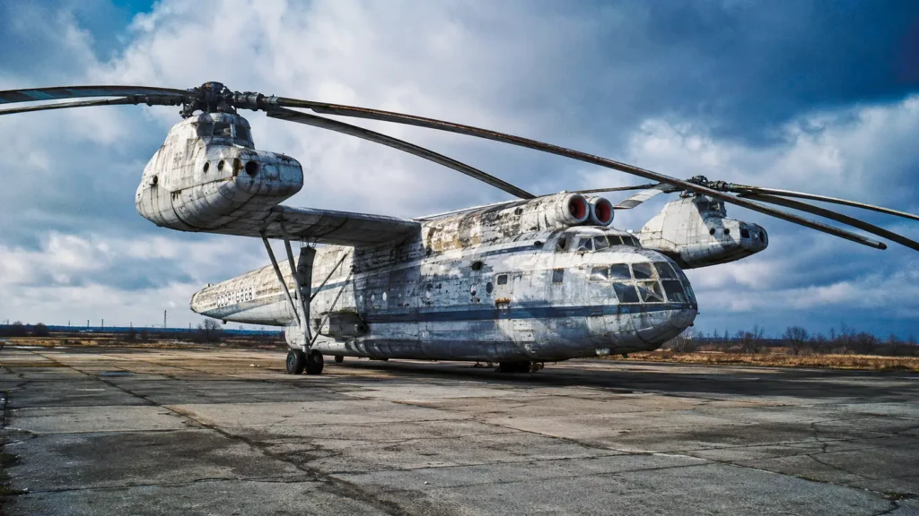 Le gigantesque hélicoptère soviétique Mil V-12 abandonné sur un tarmac russe, marqué par des décennies d’exposition aux intempéries.