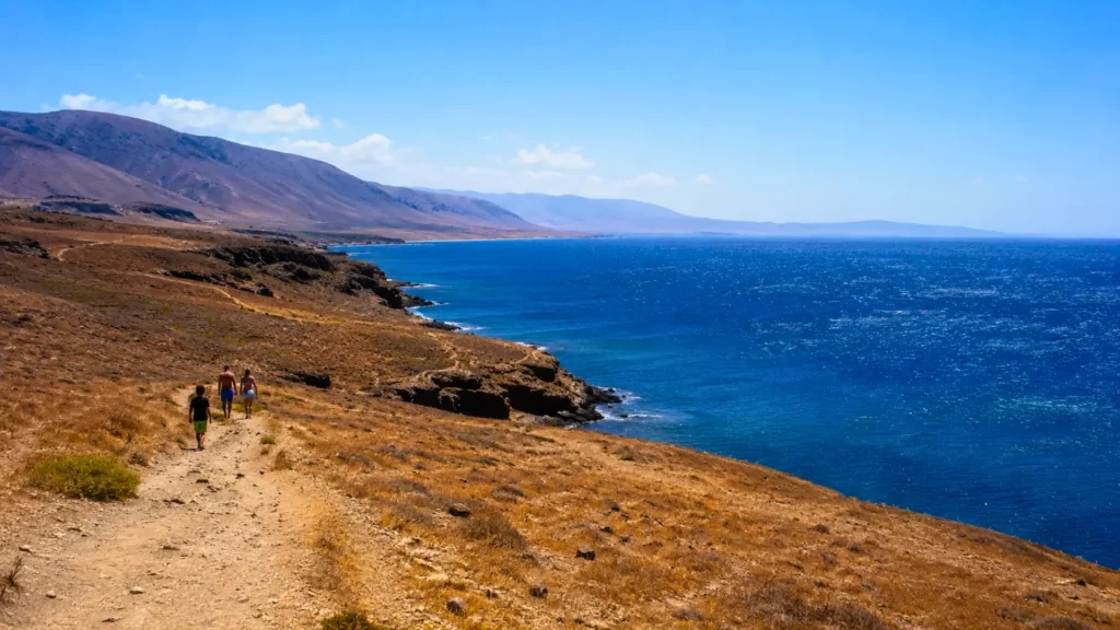 Paysage côtier aride bordé par un océan bleu, illustrant le réchauffement plus rapide des continents par rapport aux océans.