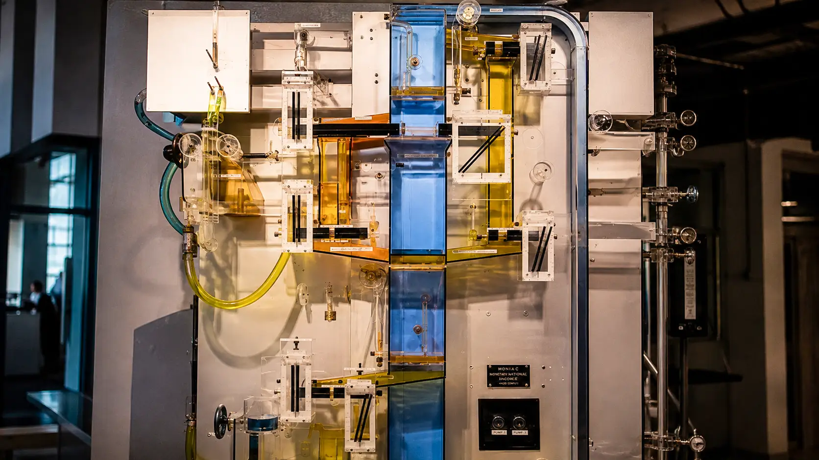 Le MONIAC, ordinateur hydraulique conçu en 1949, utilise des réservoirs, des tuyaux et de l’eau colorée pour simuler les flux économiques.