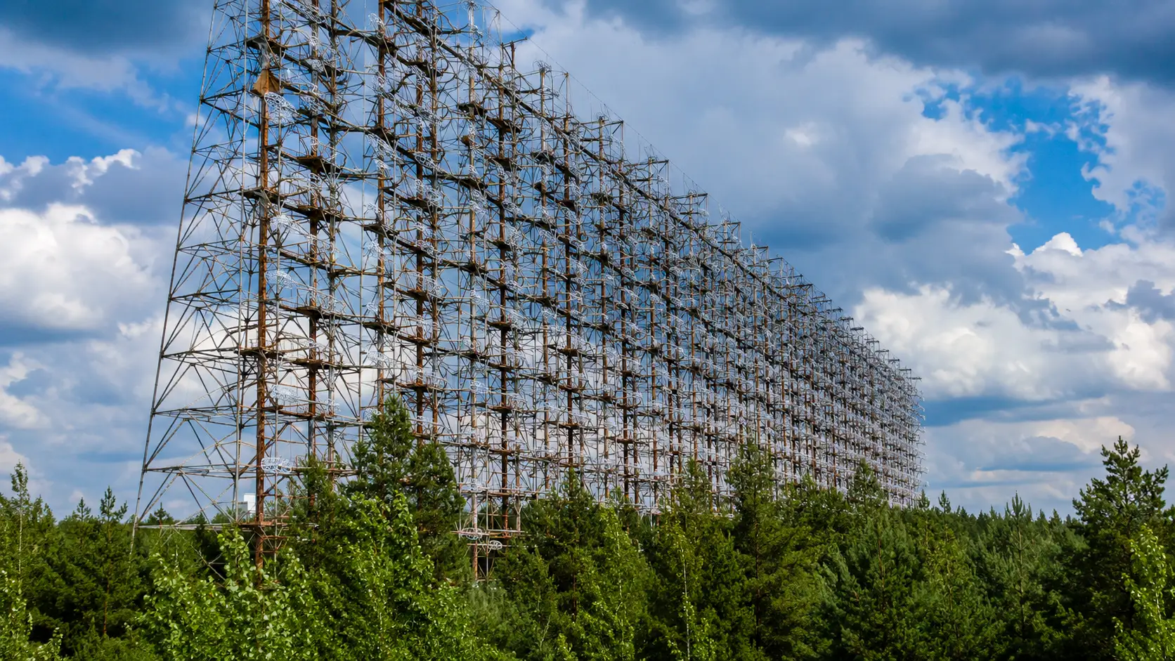 Le gigantesque radar soviétique Duga domine la forêt de Tchernobyl, sa structure d’acier rouillée s’étendant au-dessus de la canopée.