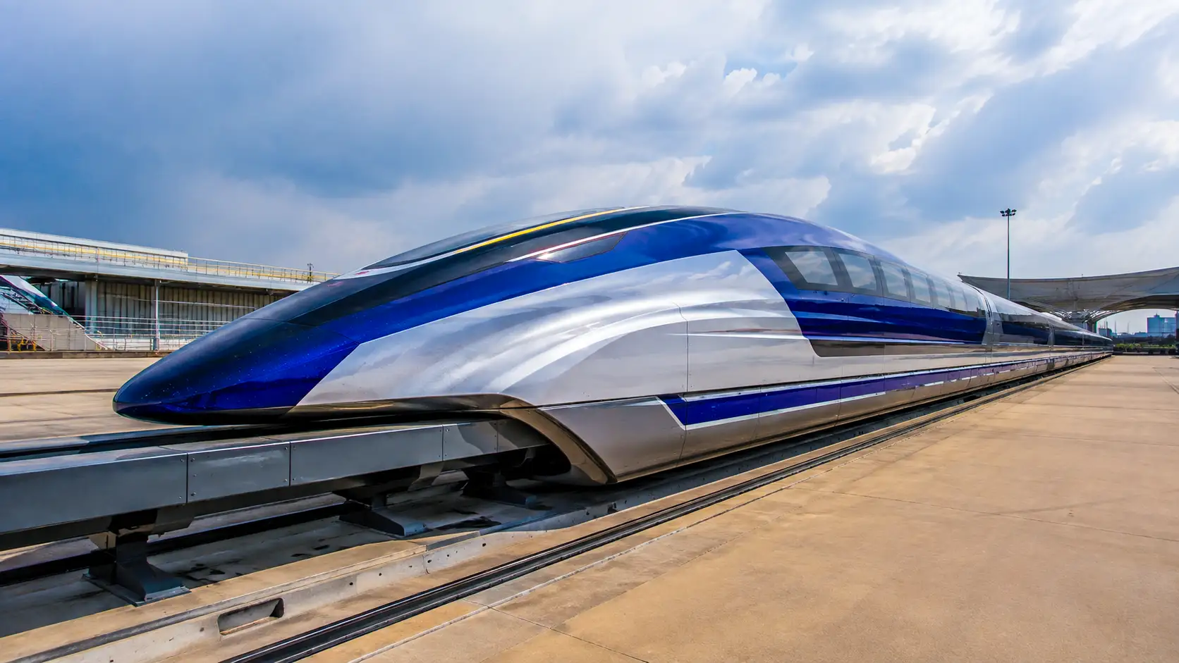 Un train à sustentation magnétique chinois au design futuriste reste immobilisé sur une voie d’essai sous un ciel nuageux.