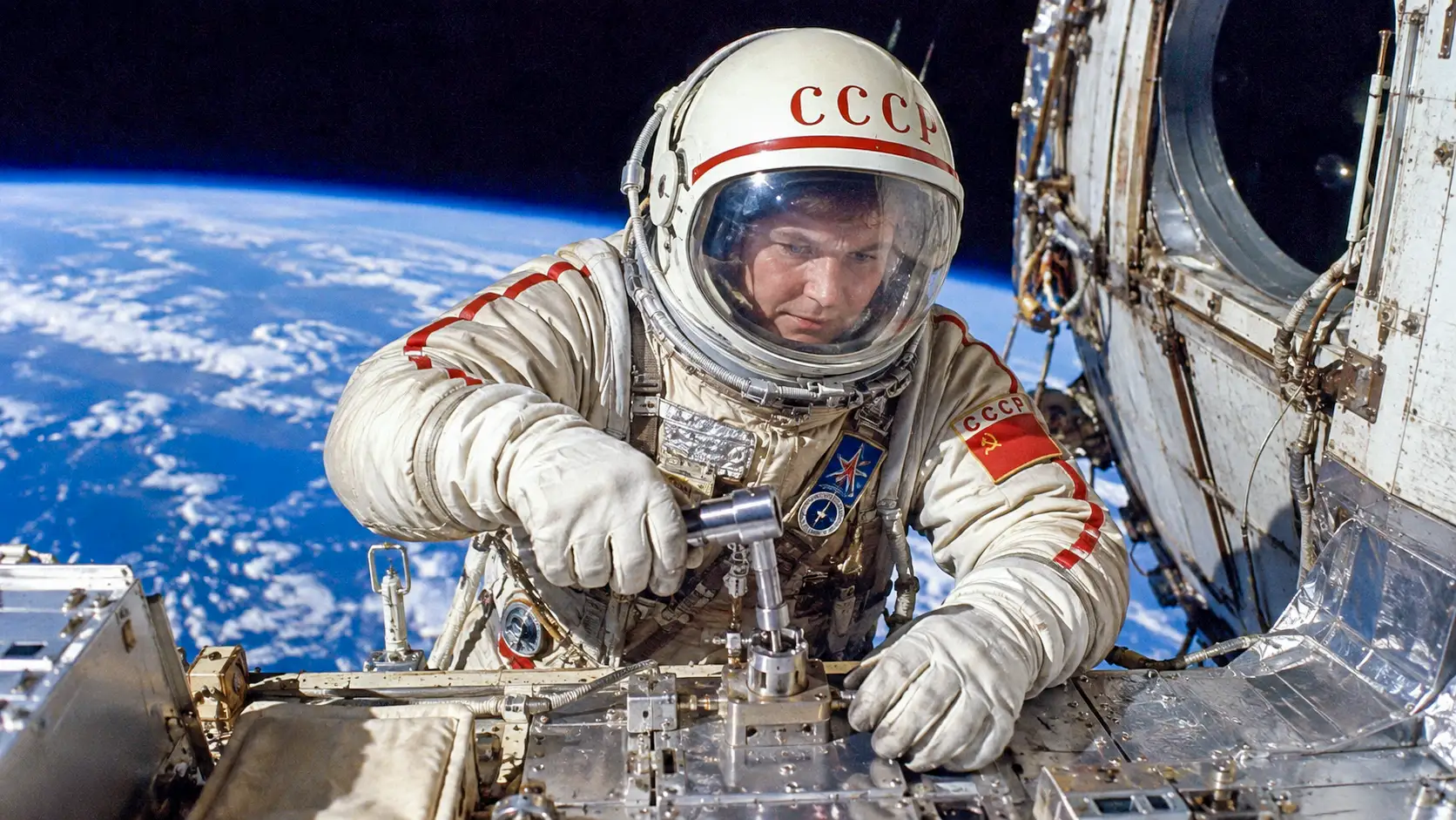 Une cosmonaute soviétique manipule un outil métallique lors d’une sortie dans l’espace.