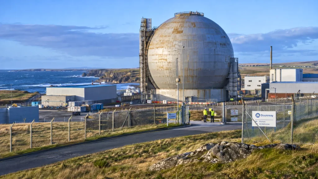 Sphère métallique de 41 mètres du réacteur nucléaire de Dounreay sur la côte écossaise, entourée d’installations industrielles et de clôtures de sécurité.