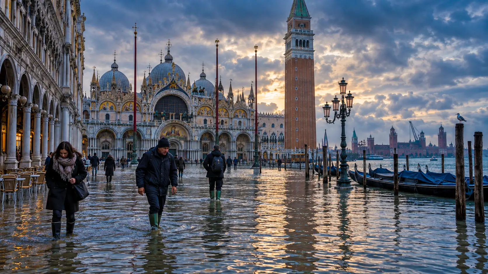 La place Saint-Marc à Venise submergée par l’acqua alta, tandis que des passants traversent l’eau devant la basilique et le campanile.