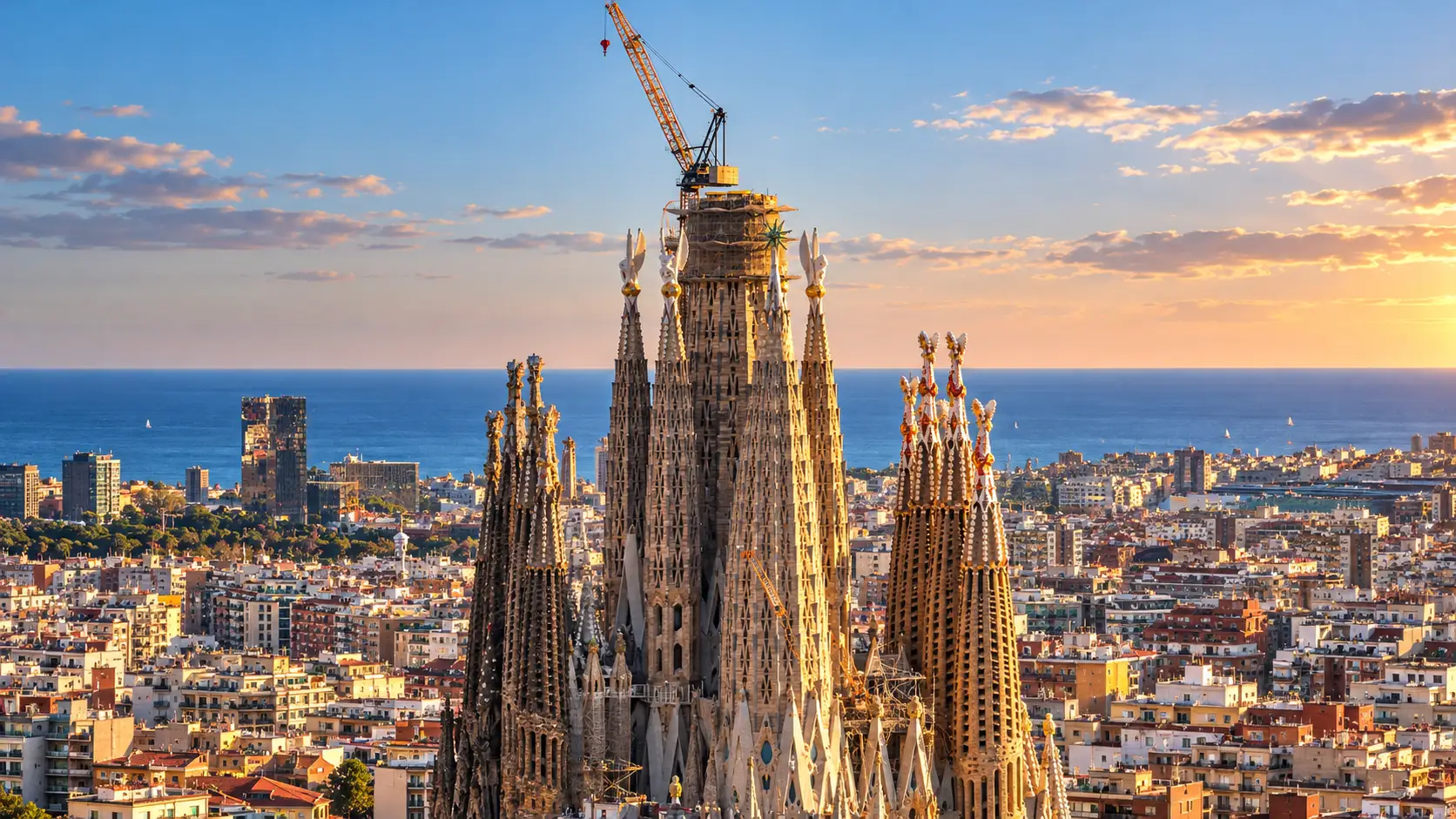 La Sagrada Família domine Barcelone avec ses tours monumentales et une grue encore visible au sommet du chantier.